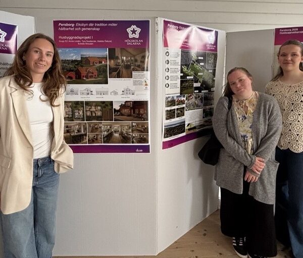 Tre kvinnliga studenter som står framför sina posters