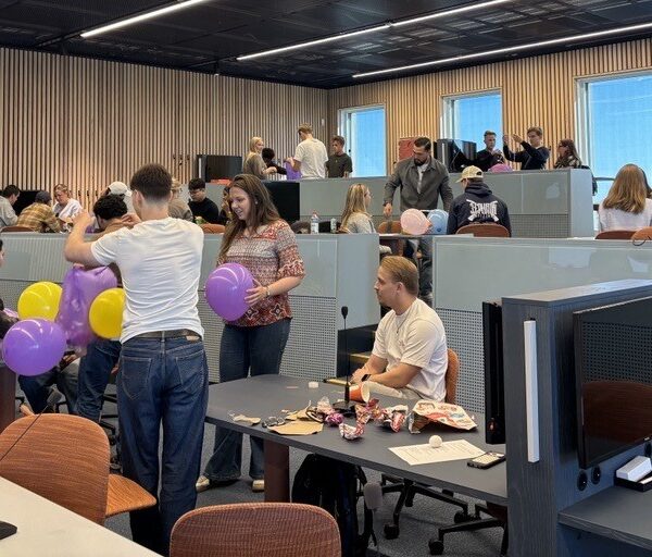 Flera studenter sitter i olika grupper och jobbar med bland annat ballonger