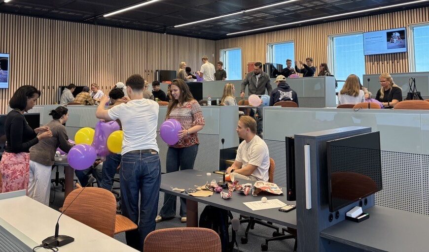 Flera studenter sitter i olika grupper och jobbar med bland annat ballonger